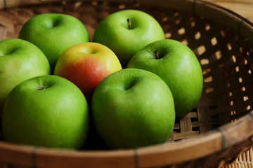 Set of green apple surround red apple in wood basket on wood mat and have some space for write wording, trendy delicious fruit for health concern people especially for weight control women or men
