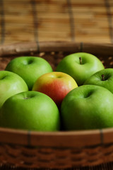 Set of green apple surround red apple in wood basket on wood mat and have some space for write wording, trendy delicious fruit for health concern people especially for weight control women or men