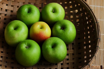 Set of green apple surround red apple in wood basket on wood mat and have some space for write wording, trendy delicious fruit for health concern people especially for weight control women or men