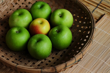 Set of green apple surround red apple in wood basket on wood mat and have some space for write wording, trendy delicious fruit for health concern people especially for weight control women or men