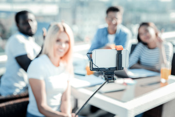 Pose on camera. Silhouette of pretty blonde that expressing positivity and sitting near her friends, doing selfie