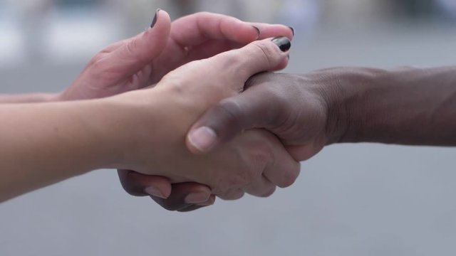 hands of white woman shaking hands of black man. anti-racism ,multiculturalism