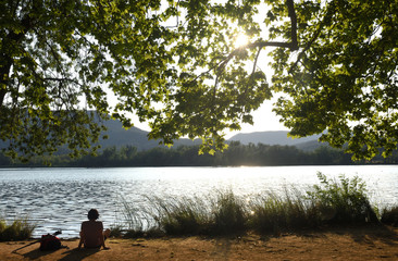 Fototapeta na wymiar Woman looking at a lake when the sun sets