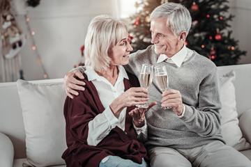 Loving couple. Delighted female person talking to her husband and holding bocal in right hand while feeling happiness