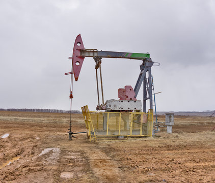 The beam pumping unit is homework, sunset in oil field. Oil pump oil rig energy industrial machine for petroleum. The pumping unit as the pump installed on a well. Equipment of oil fields.