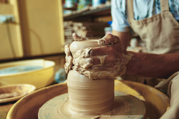 Creating a jar or vase of white clay close-up. Master crock. Man hands making clay jug macro.