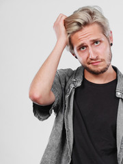 Standing blonde man being confused scratching head