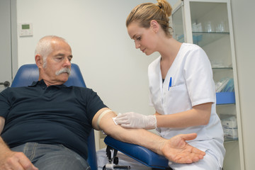 Obraz premium Nurse taking blood from elderly male patient