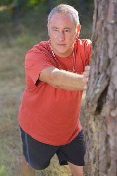 elderly man stretching on a tree