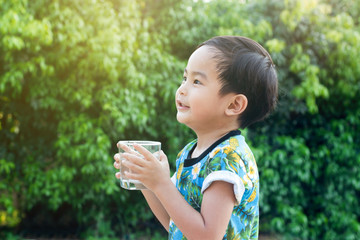 Asian Cute smile Boy drinking water for Healthy and Refreshing with green tree background.