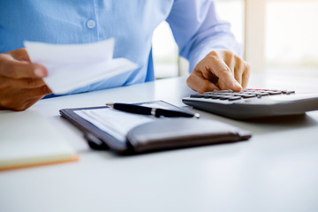Woman with bills and calculator. Woman using calculator to calculate bills at the table in office. Calculation of costs.