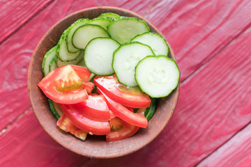 Salad of fresh tomatoes and cucumbers. Sliced tomatoes and cucumbers in a deep plate.