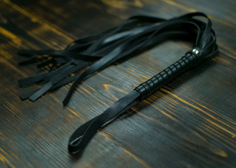 Whip for BDSM  on a dark background. Accessory for sexual games.