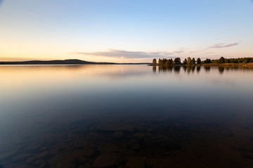 Stones underneath the surface. Beautiful sunset on lake Inari in Lapland, Finland.