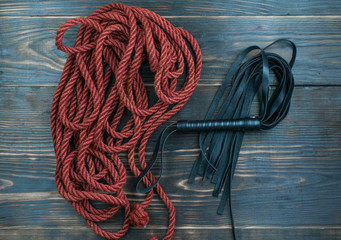 Whip for BDSM and rope to tie on a dark background. Accesories for sexual games.