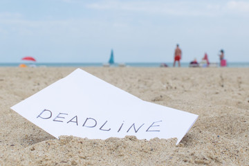 Deadline. The inscription on paper is buried in the sand.