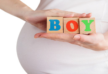 Closeup of pregnant woman holding wooden blocks with boy sign isolated on white