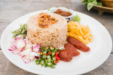 "Kao Cluk Ka Pi or Mixed Cooked Rice with Shrimp Paste on the wooden round dish. Thai Traditional food.