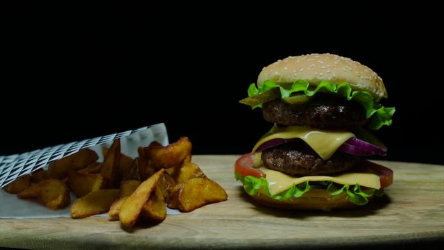 Close up of delicious burger with double cheese and french fries. Black background
