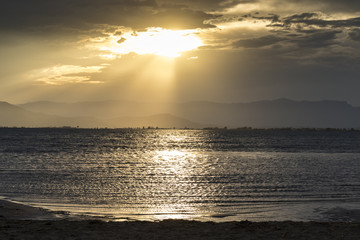 Playa de aguas doradas con rayos de sol en un amarillo atardecer