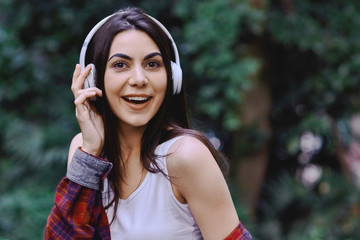 Young smiling woman listening to the music, through headphones on her head