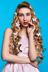 Fashion photo of young woman against blue background wearing pink dress and hair pins look like butterflies