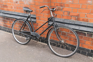 A Vintage Ladies Bicycle Leaning Against a Brick Wall.