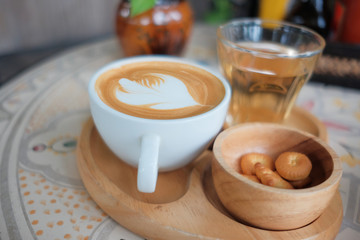 Coffee in a white cup and tea on the table.