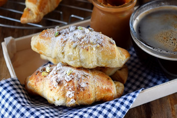 Fresh croissants sprinkled with nuts and a cup of black coffee