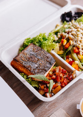 Clean food meal box: Grilled salmon fillet with tomato and bean sprout salad including carrot and corn.