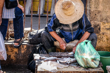 Fish monger filleting fish for customer in Moroccan fish market