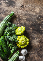 Broccoli, zucchini, squash, garlic, cucumbers - fresh organic vegetables on a wooden background, top view. Flat lay, copy space