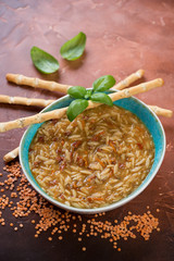 Turquiose bowl with italian thick soup including pasta and lentils, vertical shot, selective focus