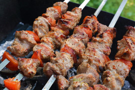 Kebab and mushrooms grilling on the skewers on the charcoals