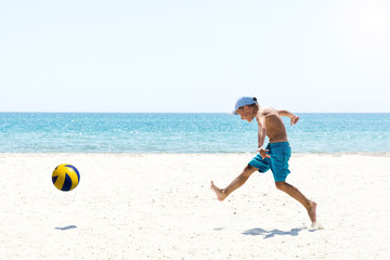 A boy playing football at the empty beach