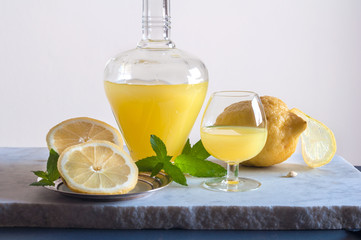 Bottiglia di limoncello e limoni di Sorrento decorati con la menta sullo sfondo chiaro