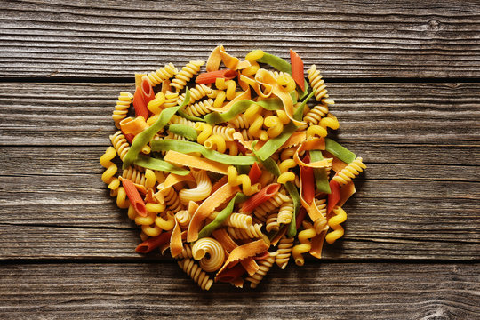 Yellow and green italian pasta heap on a wood background