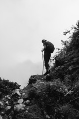 Man holding large stick hiking up a mountain