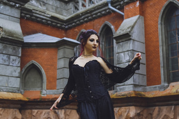 Young brunette girl in gothic style on a background architecture