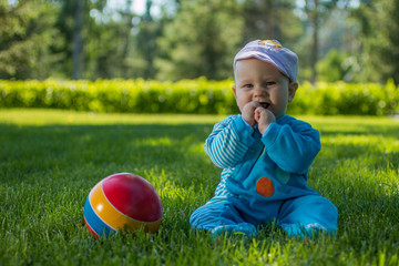 baby sitting on the soft grass in the city Park with his colorful ball