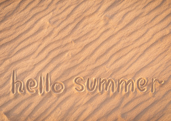 Fototapeta na wymiar The inscription on the sand. Hello summer. Beach season. Postcard. Shadows on the sand.