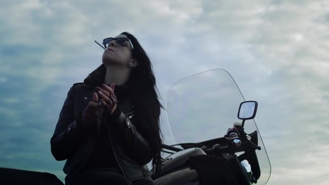 Girl biker is smoking sitting on motorcycle