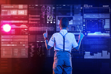 Attention. Attentive clever boy looking at the transparent screen and pointing his finger up while thinking