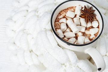 White cup of hot chocolate with marshmallows on pompon yarn. Pleasant moments.  Selective focus.