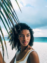 Woman in the Maldives island beach with a palm tree leaf
