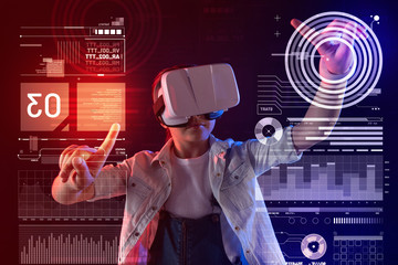 Using virtual reality. Serious pupil looking concentrated while wearing virtual reality glasses and...
