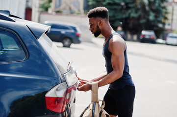Naklejka premium African american male athlete sport man with backpack against his black suv car before training.