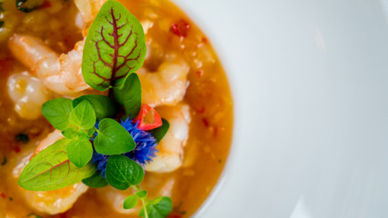 Hot Tomato soup with shrimp. Seafood creamy soup with goat cheese, olive powder, wild shrimps on bowl plate at wooden table, top view, close-up. Delicious vegetarian diet food. - obrazy, fototapety, plakaty