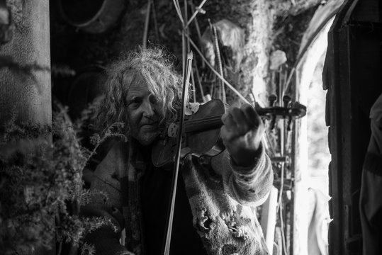 Greyscale image of an older bohemian man playing  violin