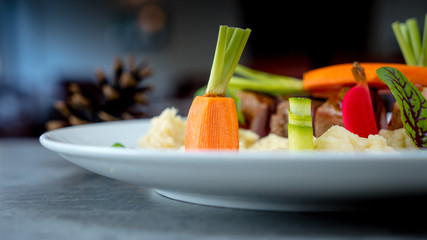Meat dishes and fresh carrots on table in restaurant